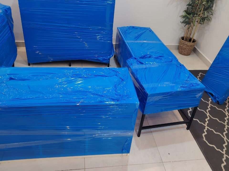 أثاث شقة مغلف بالنايلون الأزرق داخل غرفة حديثة مضيئة استعدادًا لنقله