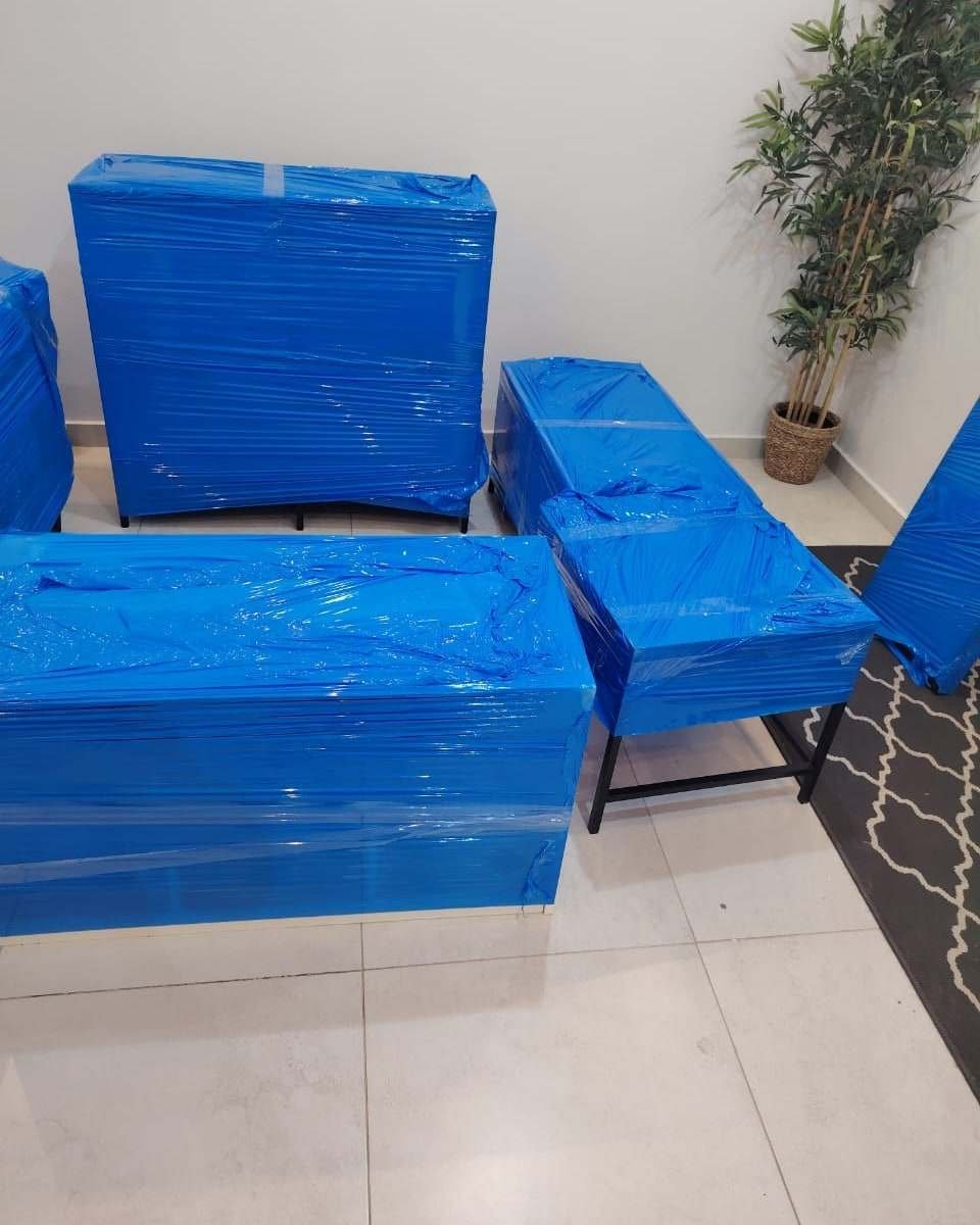 أثاث شقة مغلف بالنايلون الأزرق ومرتب في الصالة قبل التحميل
