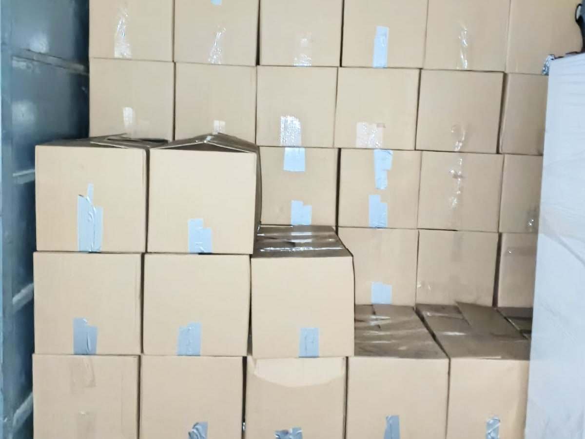 جدار من الكراتين المغلقة بالشريط اللاصق مرصوصة فوق بعضها داخل صندوق سيارة النقل