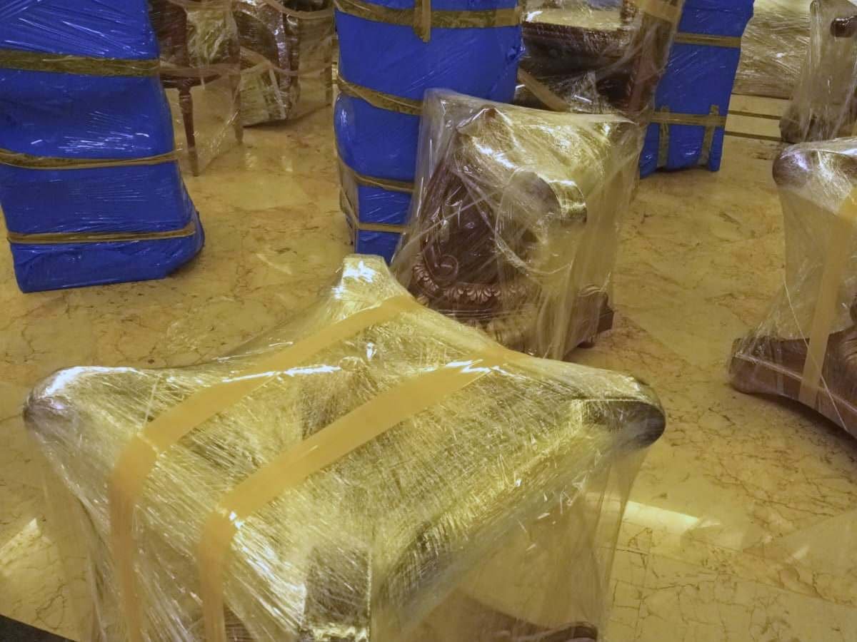 كراسي مجلس كلاسيكية وطاولات جانبية مغلفة بالنايلون الشفاف والأزرق قبل نقلها