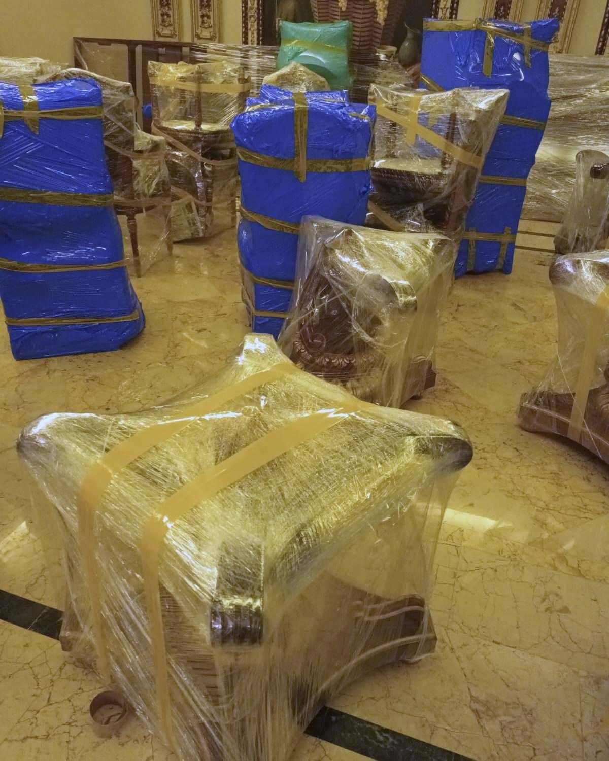 أثاث مجلس كلاسيكي وكراسي مذهبة مغلفة بالنايلون ومثبتة بالشريط قبل النقل