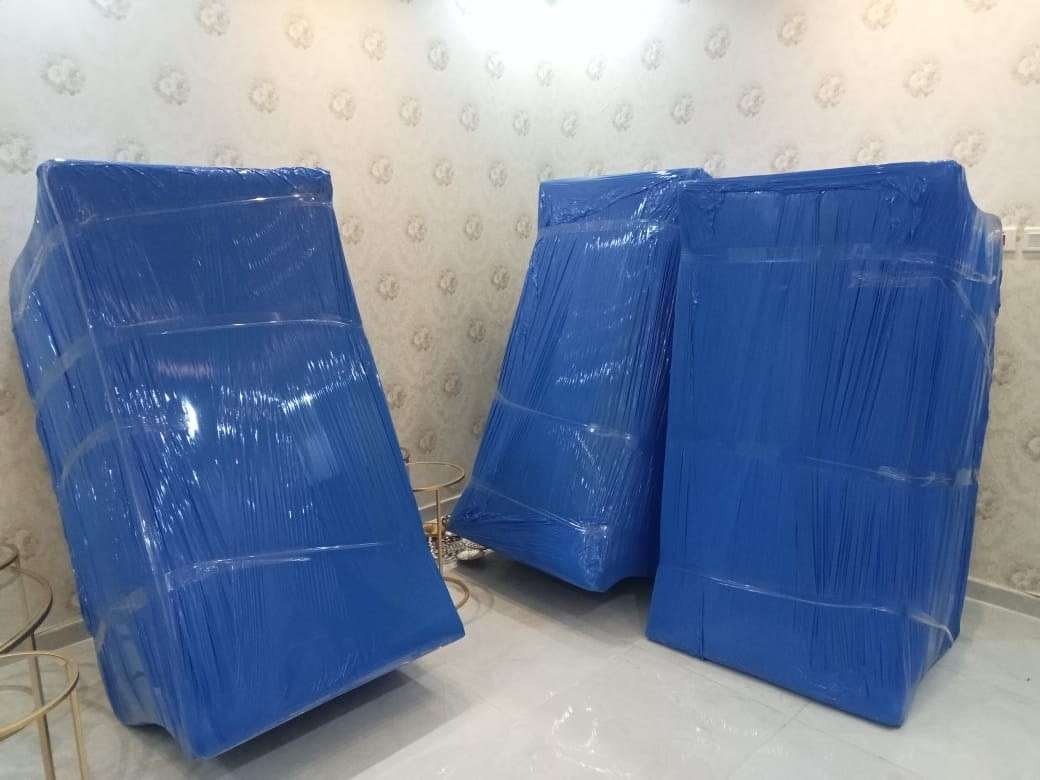 ثلاث قطع أثاث كبيرة مغلفة بالنايلون الأزرق ومربوطة بالشريط اللاصق وجاهزة للتحميل