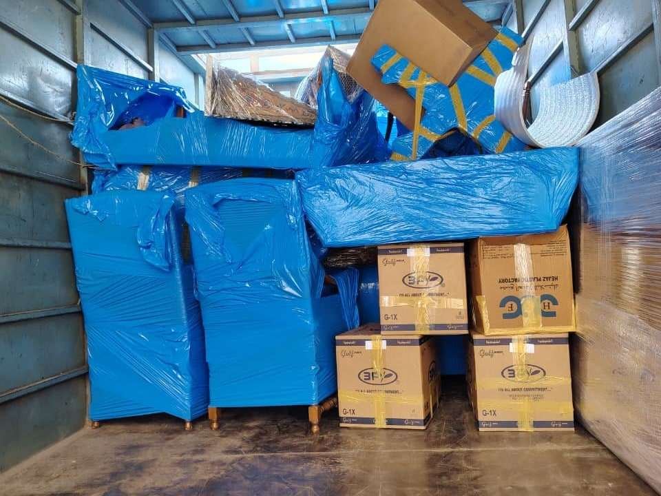 أثاث مغلف بالنايلون الأزرق وكراتين مغلقة بالشريط اللاصق مرصوصة داخل صندوق سيارة النقل