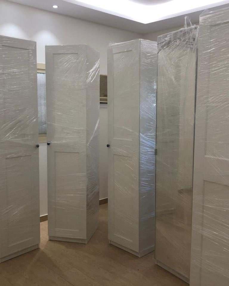 دواليب بيضاء مغلفة بالنايلون الشفاف وجاهزة للنقل إلى البيت الجديد